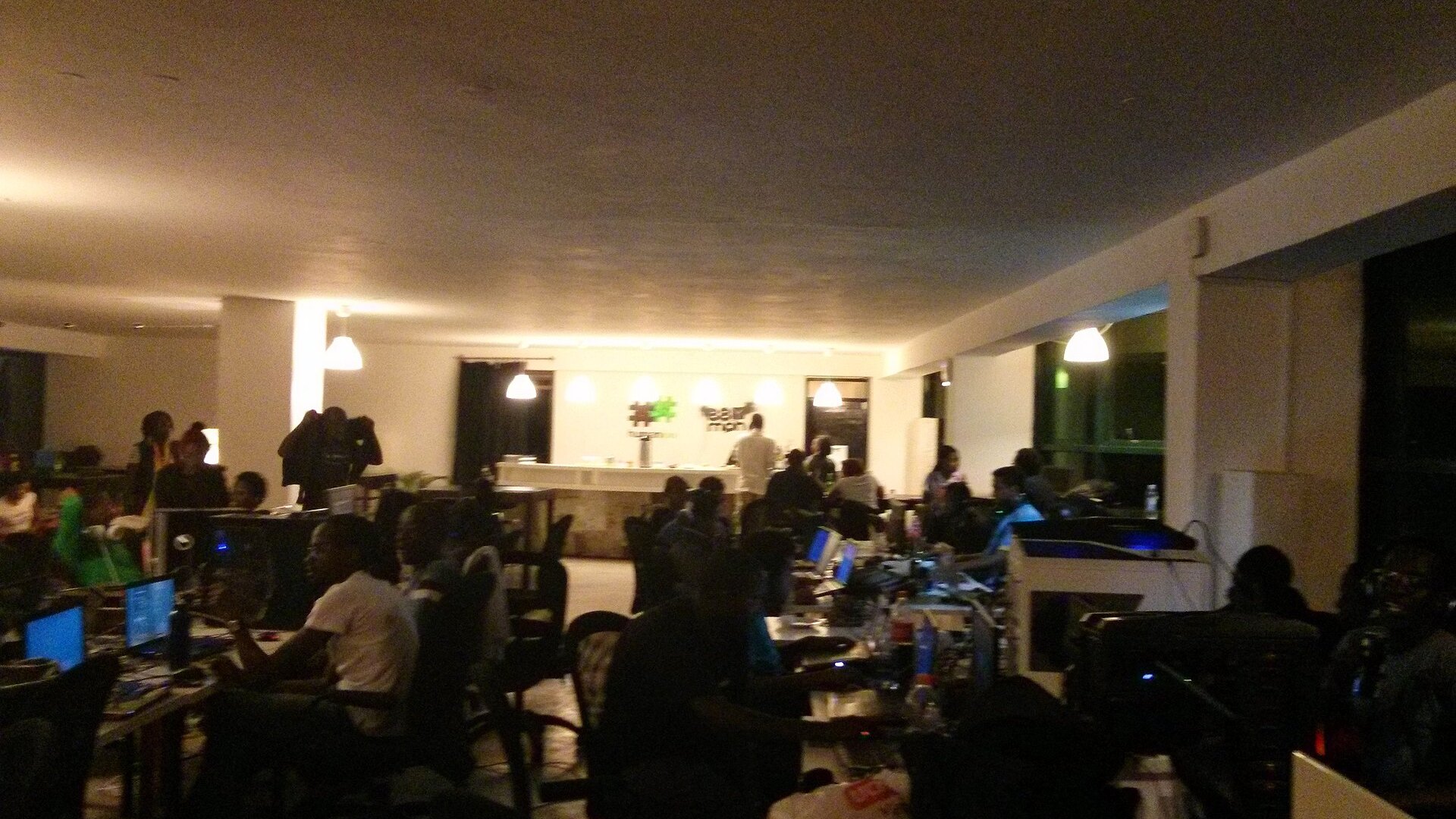 Busy student LAN gaming club with rows of stations and players mid-session